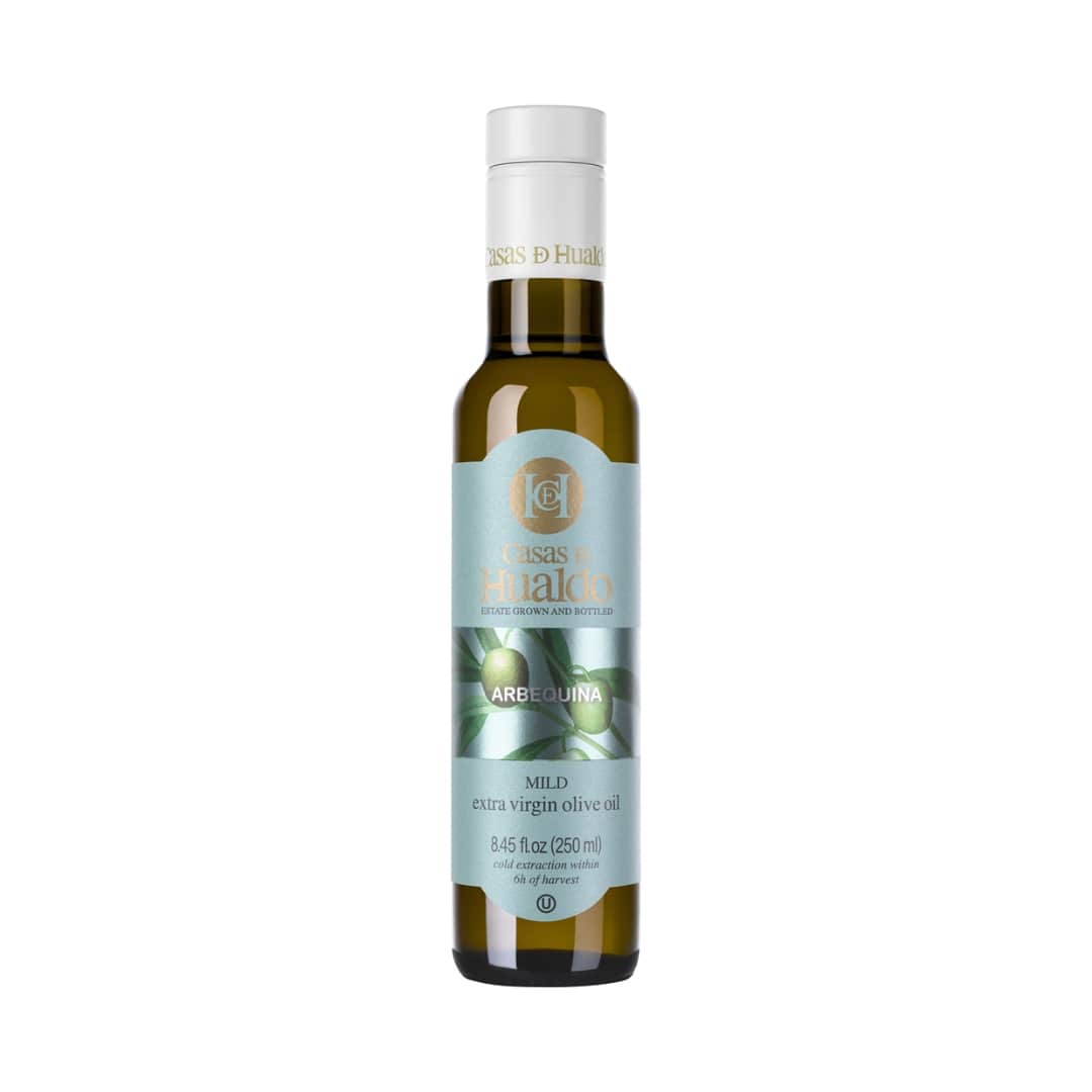 The CASAS DE HUALDO Extra Virgin Olive Oil Arbequina comes in an 8.45 fl oz bottle with a green and white label featuring olives. It is prominently labeled Mild, reflecting its premium quality and delightful flavor.