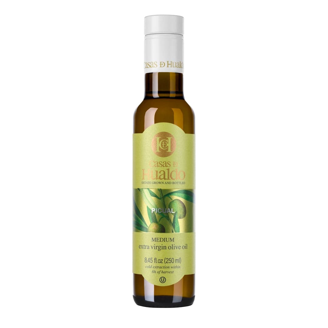 A 250 ml bottle of CASAS DE HUALDO Extra Virgin Olive Oil Picual by Casas de Hualdo, featuring a green and yellow label with Medium and Picual, offers the rich taste of premium Picual olives.