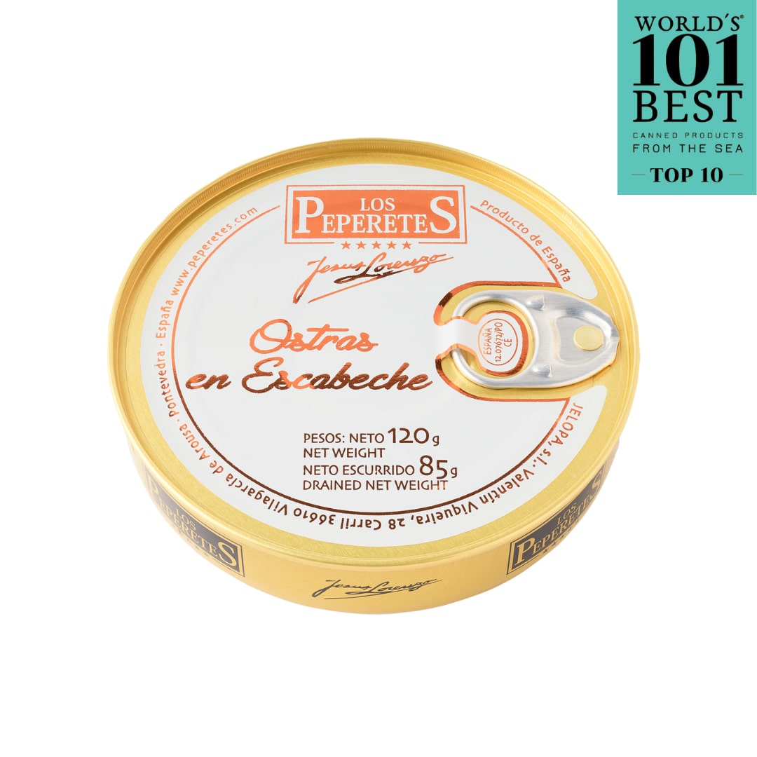 A round tin of LOS PEPERETES Oysters in Escabeche sits on a white background. The can, with a pull-tab lid, features an award label at the top right, declaring it among the Worlds 101 Best Canned Products from the Sea - Top 10. A true Spanish delicacy!.